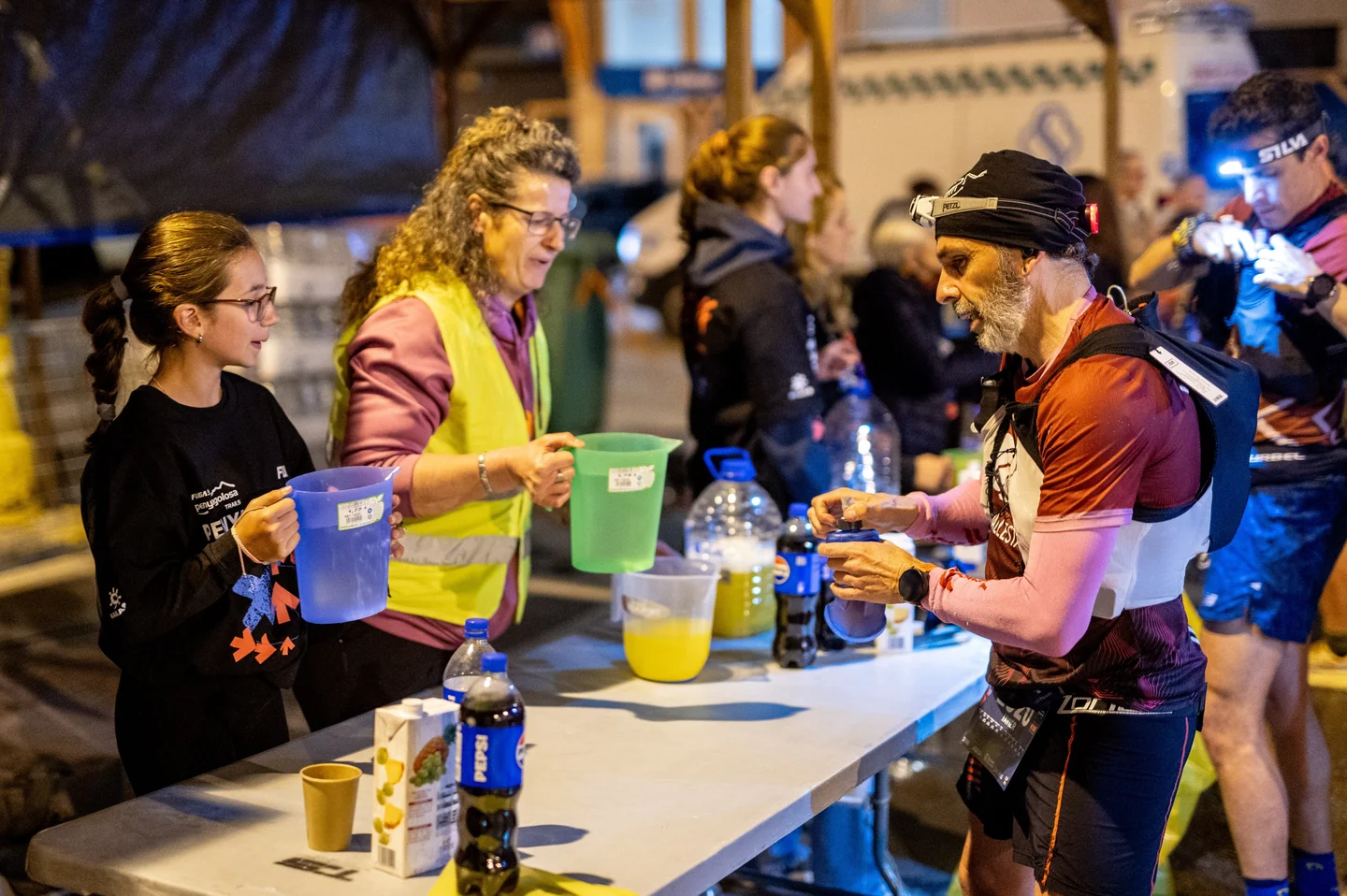 Voluntarias sirviendo bebidas a un corredor en un avituallamiento