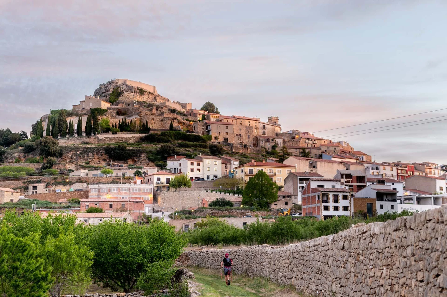 Vista de un pueblo sobre una colina con huertos y muros de piedra