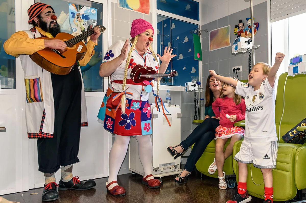 Dos artistas vestidos de payasos actuando con una guitarra